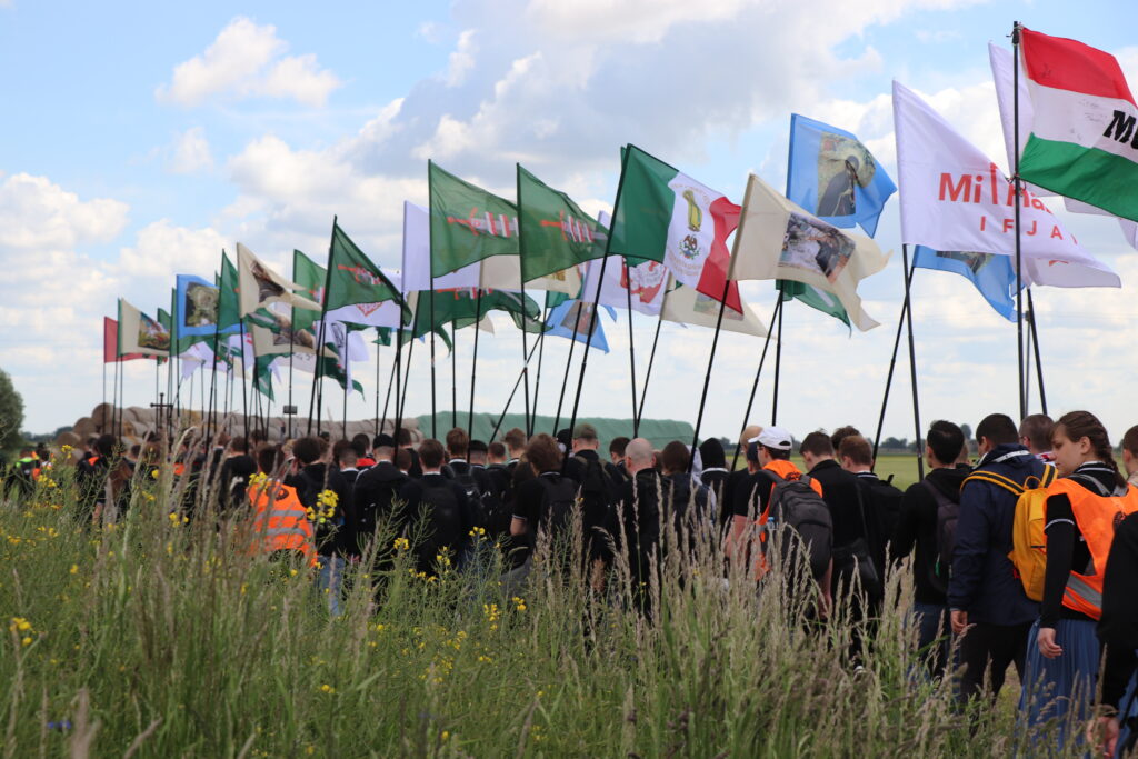  Kolumna pielgrzymkowa idąca przez pola Wielkopolski, z flagami i transparentami Pielgrzymki Kościoła Walczącego.