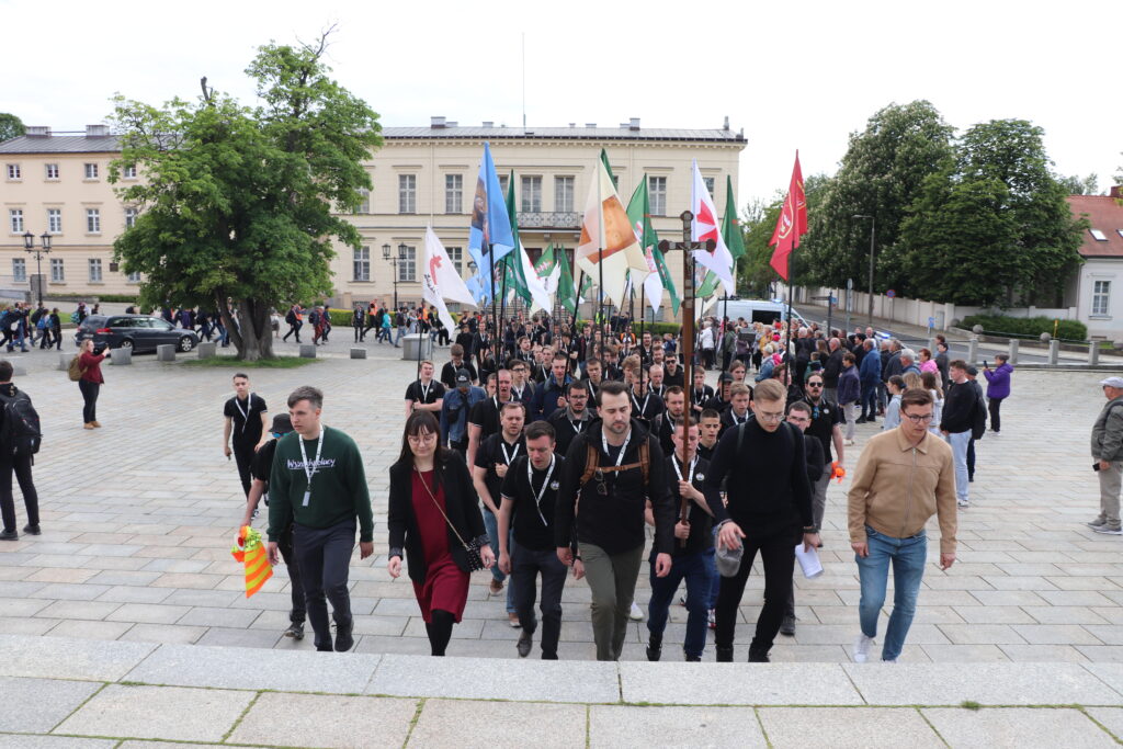 Wejście uczestników Pielgrzymki Kościoła Walczącego na wzgórze katedralne w Gnieźnie z flagami i transparentami. Na przedzie idą Bartosz Malewski - prezes SMN oraz Marcin Osowski - prezes MW.